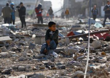 கான் யூனிஸ் மீது இஸ்ரேலிய குண்டுவீச்சினால் அழிக்கப்பட்ட வீடுகளின் இடிபாடுகளில் பாலஸ்தீனிய குழந்தை ஒன்று அமர்ந்துள்ளது. (ராய்ட்டர்ஸ்)