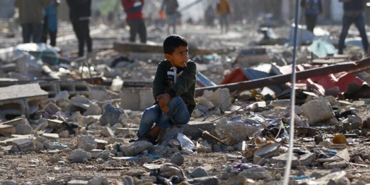 கான் யூனிஸ் மீது இஸ்ரேலிய குண்டுவீச்சினால் அழிக்கப்பட்ட வீடுகளின் இடிபாடுகளில் பாலஸ்தீனிய குழந்தை ஒன்று அமர்ந்துள்ளது. (ராய்ட்டர்ஸ்)